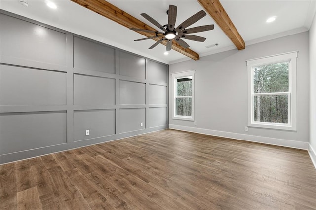 empty room featuring beam ceiling, a wealth of natural light, ceiling fan, and hardwood / wood-style floors