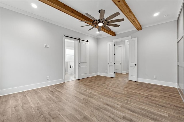 unfurnished bedroom featuring light wood-type flooring, ensuite bath, ceiling fan, beam ceiling, and a barn door