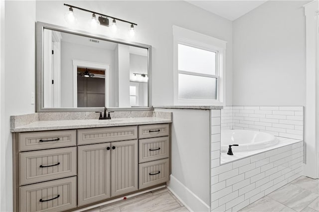 bathroom with vanity, ceiling fan, and tiled tub