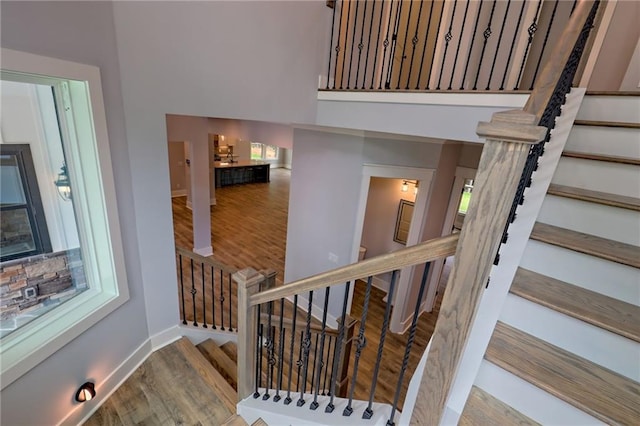 6449 Snelling Mill Rd, Flowery Branch, GA 30542 - stairs featuring a towering ceiling, wood finished floors, and baseboards