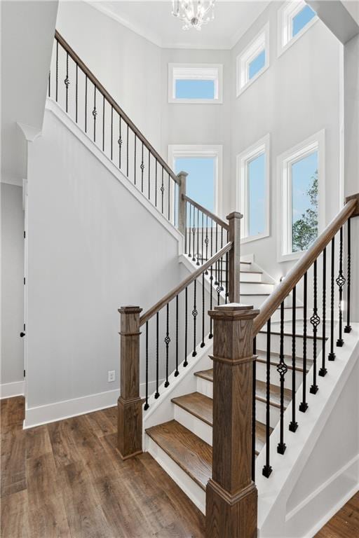 stairs featuring hardwood / wood-style flooring, plenty of natural light, an inviting chandelier, and ornamental molding