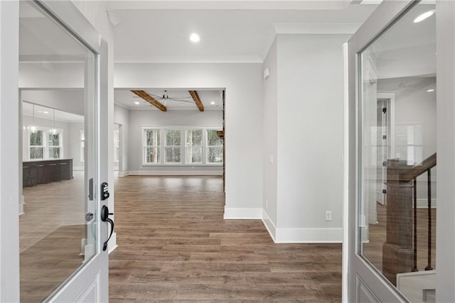 entryway with beamed ceiling, a healthy amount of sunlight, ornamental molding, and hardwood / wood-style floors