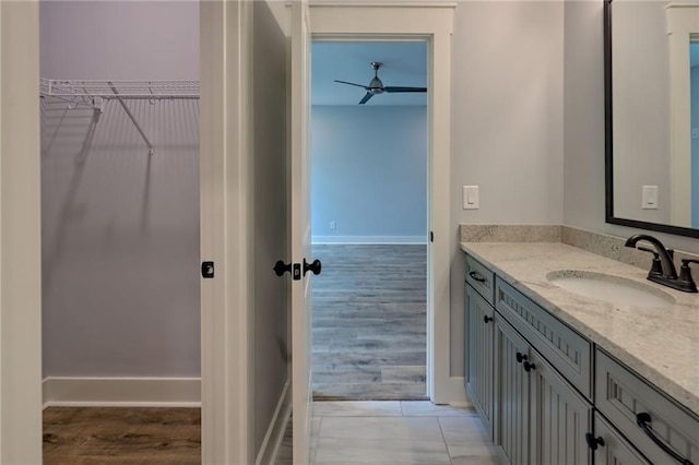 6449 Snelling Mill Rd, Flowery Branch, GA 30542 - bathroom featuring vanity, a ceiling fan, a walk in closet, baseboards, and wood finished floors