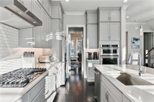 kitchen with decorative light fixtures, sink, stainless steel appliances, crown molding, and light stone countertops