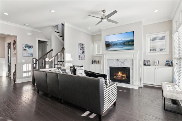 living room featuring crown molding, ceiling fan, a high end fireplace, and dark hardwood / wood-style flooring