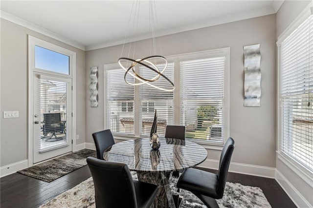 dining room featuring crown molding, dark wood-type flooring, a wealth of natural light, and an inviting chandelier