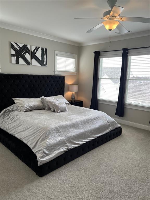 carpeted bedroom featuring ornamental molding and ceiling fan