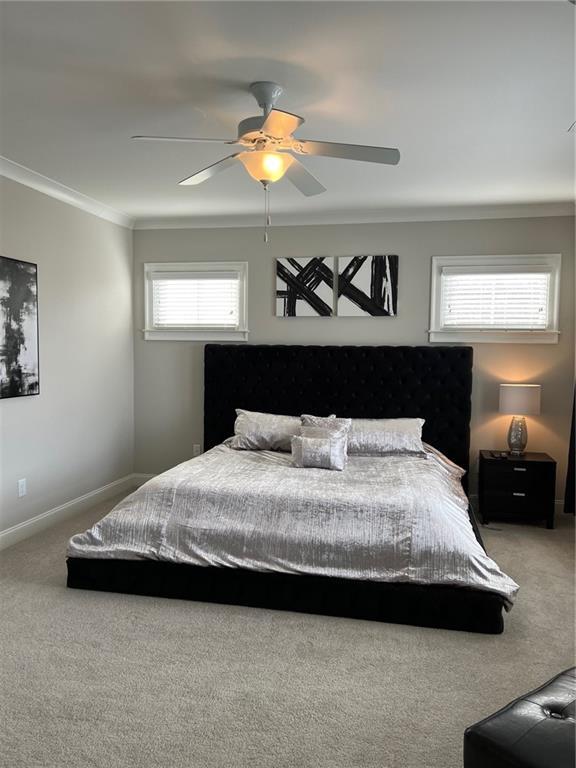 carpeted bedroom featuring ornamental molding and ceiling fan