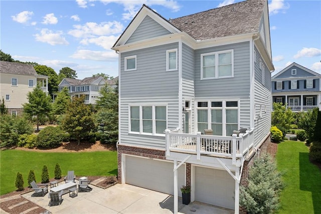 back of property with a balcony, a garage, a yard, and a patio