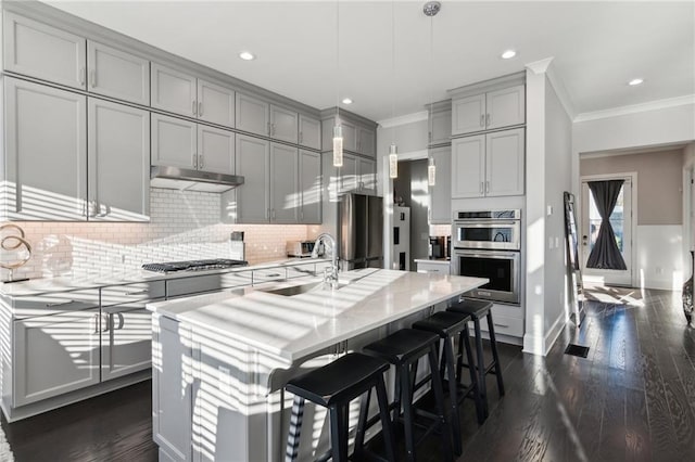 kitchen featuring a kitchen bar, sink, an island with sink, pendant lighting, and stainless steel appliances