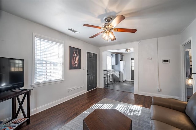 living area featuring dark wood-style flooring, visible vents, ceiling fan, and baseboards