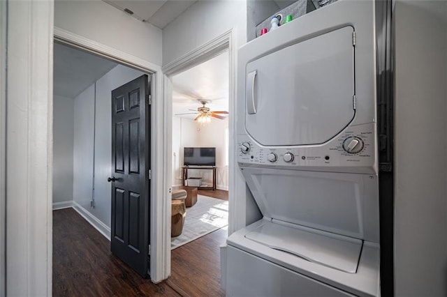 clothes washing area featuring stacked washer and clothes dryer, ceiling fan, dark wood-style flooring, and laundry area