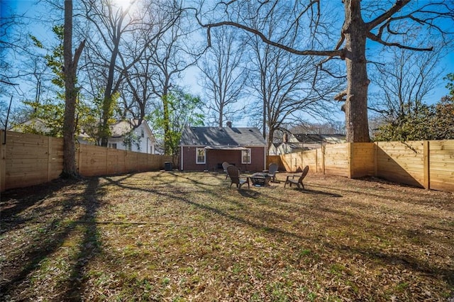 view of yard featuring a fenced backyard, an outdoor structure, and a fire pit