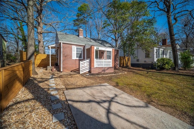 view of front facade with a front yard, brick siding, fence, and a chimney