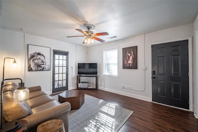 living room featuring a ceiling fan, dark wood finished floors, visible vents, and baseboards