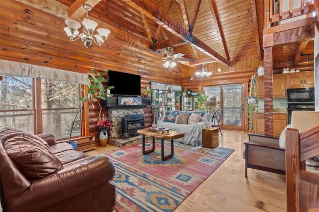 living room with beam ceiling, rustic walls, a wood stove, high vaulted ceiling, and ceiling fan with notable chandelier