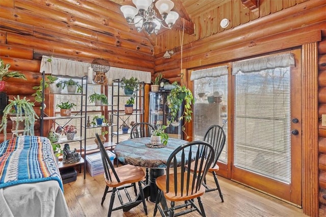 dining area featuring a notable chandelier, light wood-type flooring, and log walls