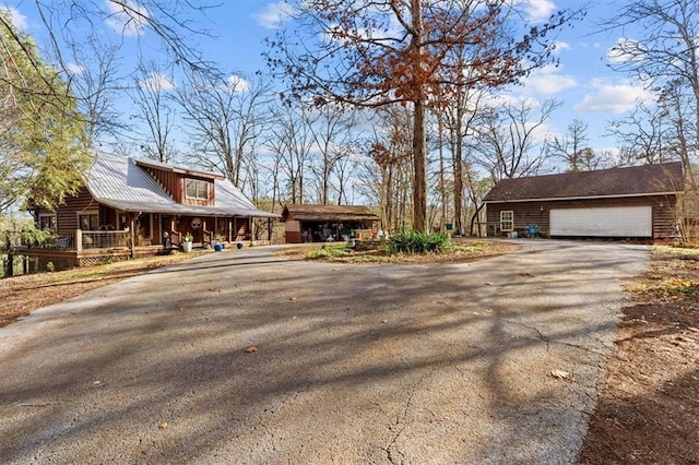 view of property exterior with a garage, covered porch, and an outbuilding