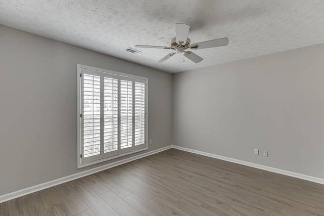 unfurnished room featuring baseboards, wood finished floors, visible vents, and ceiling fan