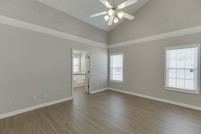 empty room with a ceiling fan, wood finished floors, baseboards, and high vaulted ceiling