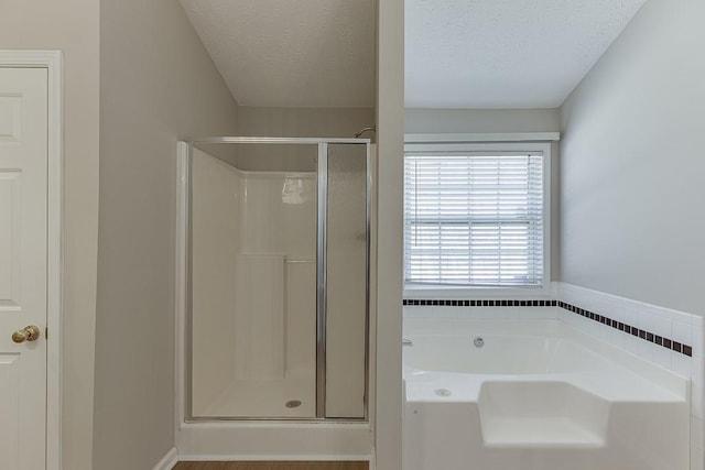 bathroom with a garden tub, a textured ceiling, and a stall shower