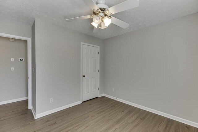 unfurnished bedroom featuring ceiling fan, baseboards, a textured ceiling, and wood finished floors