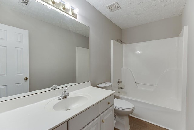 bathroom featuring visible vents, a textured ceiling, vanity, and toilet