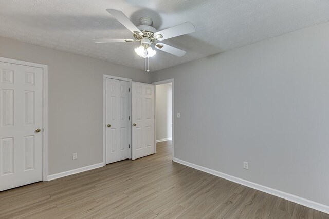 unfurnished bedroom featuring light wood-style flooring, baseboards, and a textured ceiling