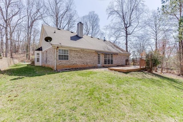 back of property with a lawn, a chimney, a deck, and brick siding