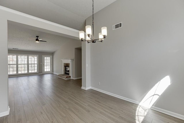 unfurnished living room with vaulted ceiling, wood finished floors, a fireplace, and visible vents