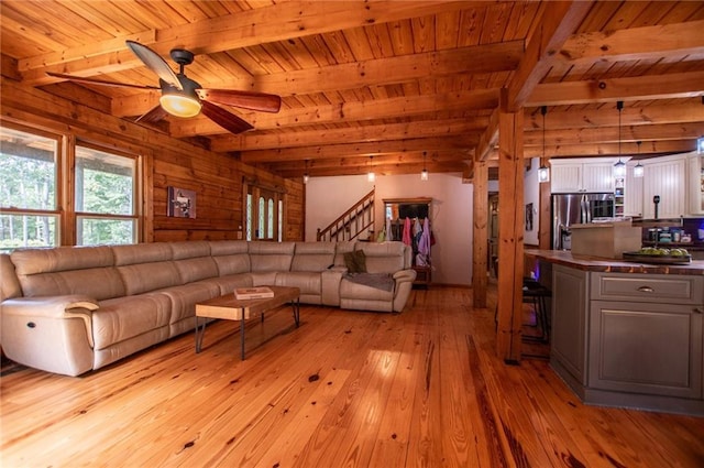 living area with a ceiling fan, light wood-type flooring, beam ceiling, stairway, and wooden ceiling