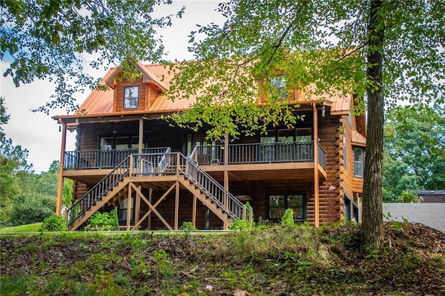 rear view of house featuring stairs, log siding, and metal roof