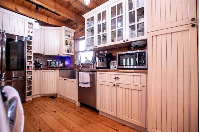 kitchen featuring dark countertops, beam ceiling, light wood finished floors, stainless steel appliances, and wood ceiling