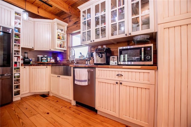 kitchen featuring wood ceiling, dark countertops, appliances with stainless steel finishes, beam ceiling, and light wood-style flooring