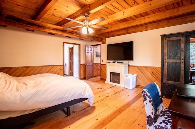 bedroom featuring a fireplace, wood walls, a wainscoted wall, wooden ceiling, and beamed ceiling