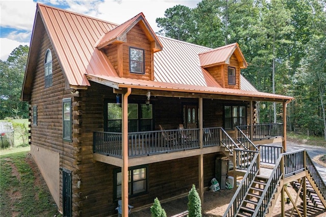 view of front of home with a deck, metal roof, stairway, and log siding