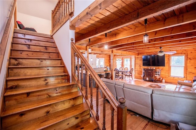living area with a healthy amount of sunlight, wood walls, stairs, and wood finished floors