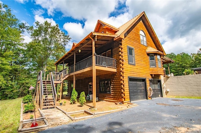view of front of house featuring fence, log siding, a garage, stairway, and driveway