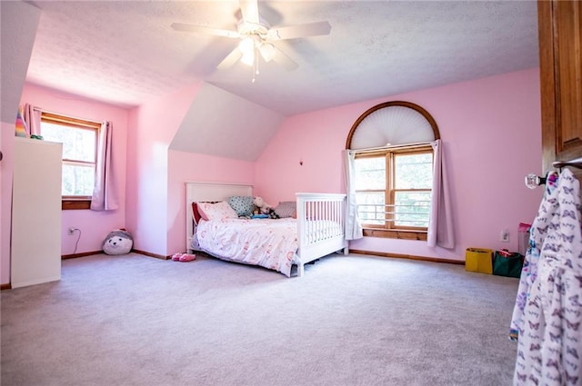 carpeted bedroom with a textured ceiling, ceiling fan, multiple windows, and baseboards