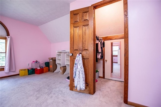 rec room featuring carpet, lofted ceiling, a textured ceiling, and a wealth of natural light