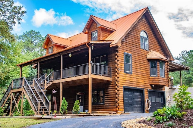 view of front facade with an attached garage, driveway, log siding, and stairs