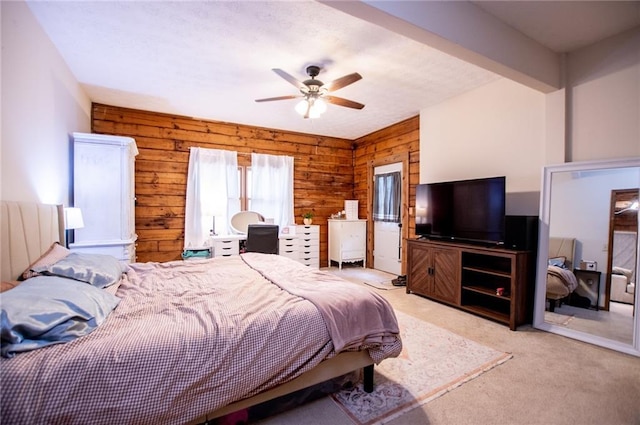 bedroom with light colored carpet, ceiling fan, and wooden walls
