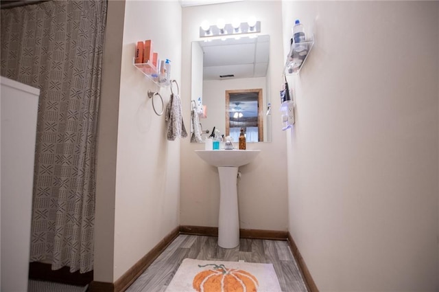 bathroom featuring baseboards, a shower with curtain, and wood finished floors