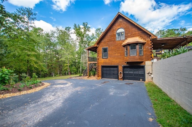 view of front of property with stairs, a garage, driveway, and log siding