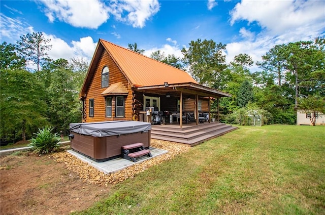 rear view of house featuring a wooden deck, log exterior, metal roof, a hot tub, and a yard