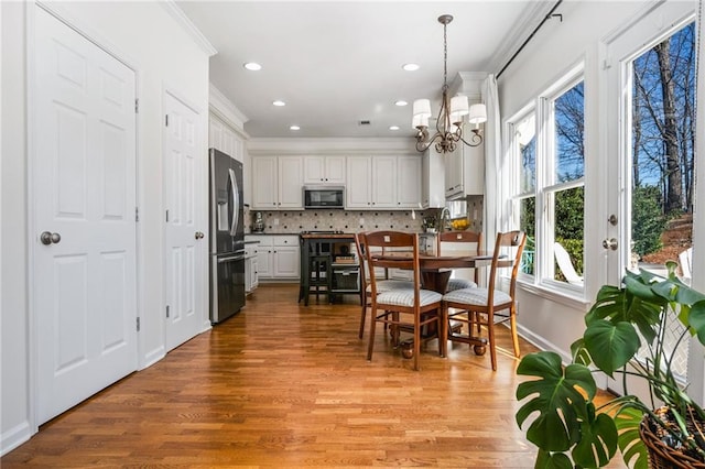 dining room with ornamental molding, a notable chandelier, and light hardwood / wood-style flooring