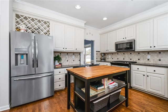 kitchen with white cabinetry, backsplash, dark wood-type flooring, appliances with stainless steel finishes, and crown molding