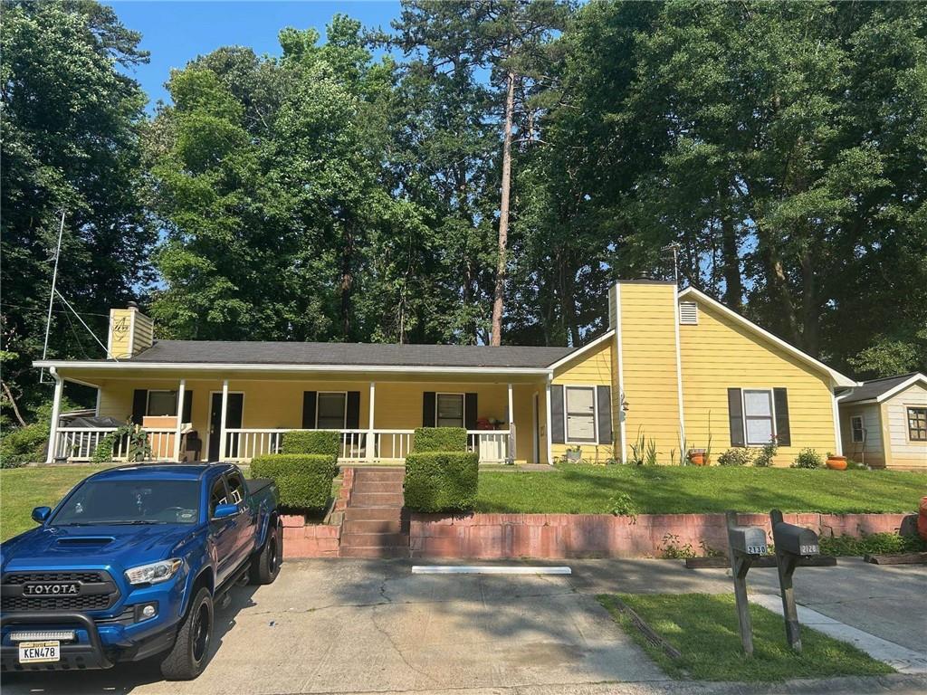 2128 Valley Oaks Dr, Smyrna, GA 30080 - view of front facade with a chimney, covered porch, and a front lawn