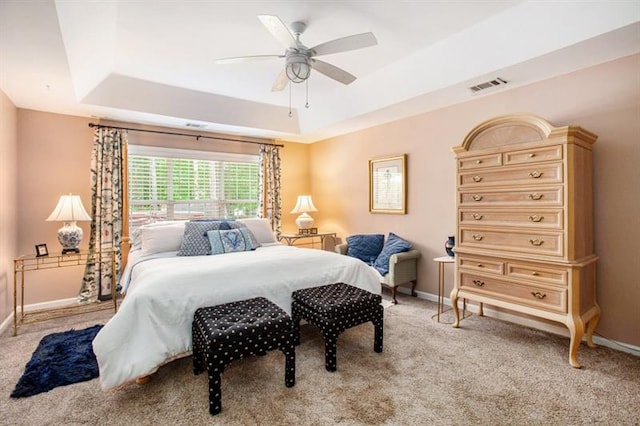 bedroom with light carpet, a tray ceiling, and ceiling fan