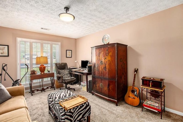 carpeted home office featuring a textured ceiling